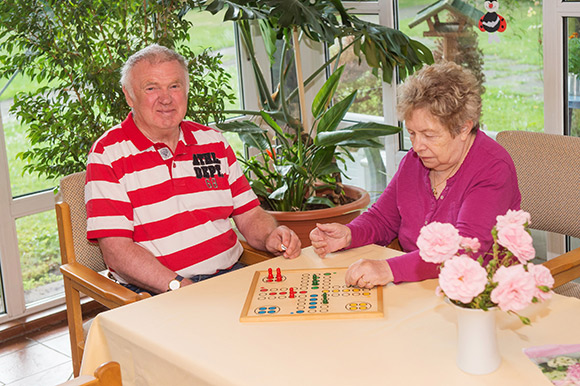 Zwei ältere Menschen sitzen am Tisch und spielen ein Brettspiel