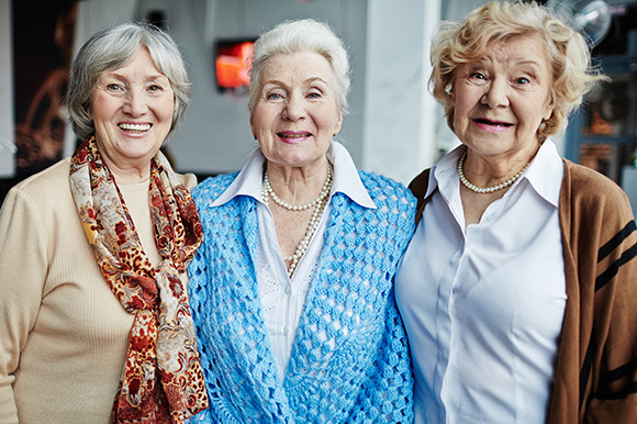 Drei freundliche Damen, die in die Kamera lächeln
