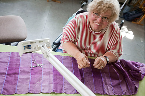Eine Frau bearbeitet einen lilafarbenen Schal
