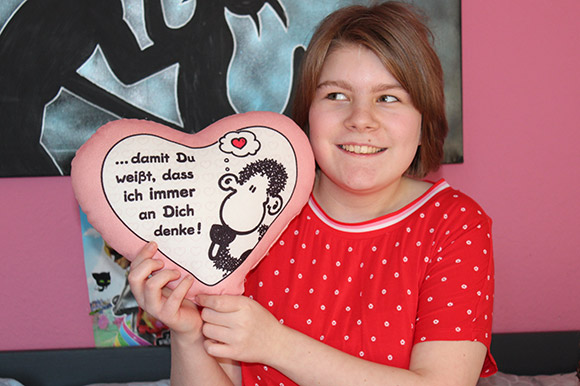 Ein Mädchen hält ein Herz-Kissen in die Kamera