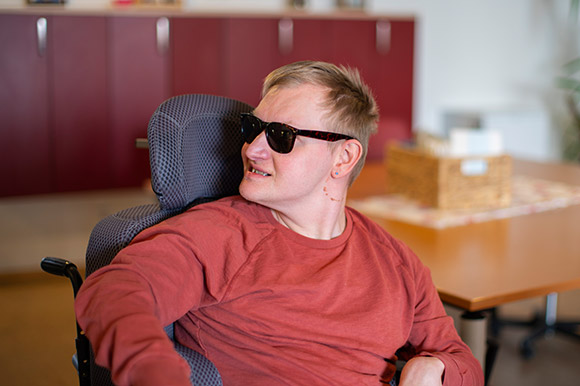 Ein Mann im Rollstuhl der eine Sonnenbrille trägt