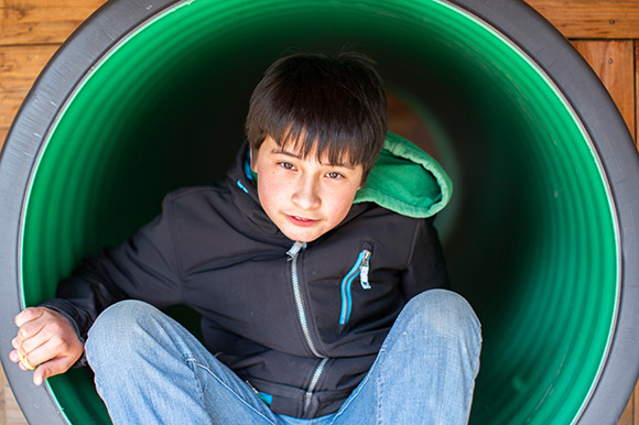 Ein Kind schaut aus einem Spielplatztunnel