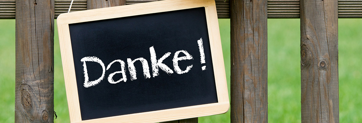 An einem Holzzaun hängt eine Kreidetafel auf der "Danke!" steht
